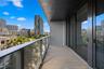Covered balcony featuring wood-finish flooring, glass panel railings, and full-height sliding glass doors