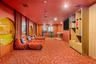 Custom media room featuring circular wall accents, built-in floor-to-ceiling shelving with cabinetry, patterned wall-to-wall carpeting, and recessed c