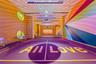 Indoor pickle ball court featuring a high-contrast athletic surface, circular windows, linear ceiling lighting, mirrored spherical pendants, and custo