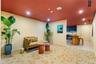 Interior space featuring a recessed ceiling with integrated lighting, patterned carpeting, and a kitchen area with built-in dark cabinetry and shelvin