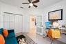 Interior room featuring neutral tile flooring, a multi-panel closet with white doors, a ceiling fan with integrated lighting, and a white interior doo