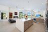 Open-concept kitchen featuring an oversized island with quartz countertops, wood-finish cabinetry, built-in stainless steel double ovens, recessed lig