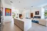 Large kitchen island with a neutral-toned countertop and wood-finish cabinetry, linear built-in fireplace, recessed lighting, and tile flooring