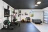 Garage space featuring high-contrast black ceiling paint, epoxy-coated flooring, and overhead LED lighting