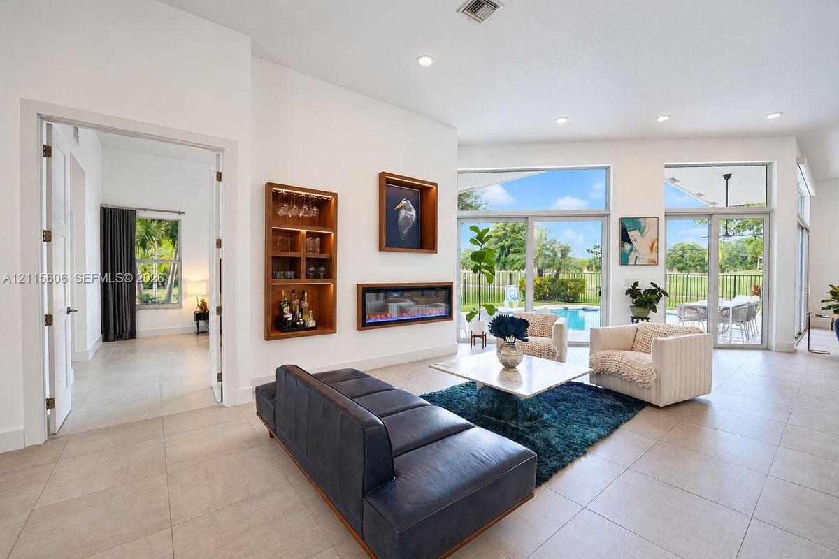 Living area featuring large-format tile flooring, recessed lighting, a linear electric fireplace, and floor-to-ceiling glass sliding doors