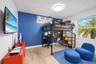 Room featuring wood-finish flooring, a vibrant blue accent wall, and a large horizontal window