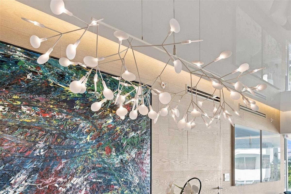 Sculptural multi-arm pendant fixture with matte white finish and frosted glass globes, paired with wood-panel feature wall and recessed cove lighting