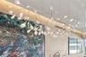 Sculptural multi-arm pendant fixture with matte white finish and frosted glass globes, paired with wood-panel feature wall and recessed cove lighting