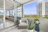 Covered balcony with a metal railing and light-colored flooring, accessed via floor-to-ceiling glass sliding doors