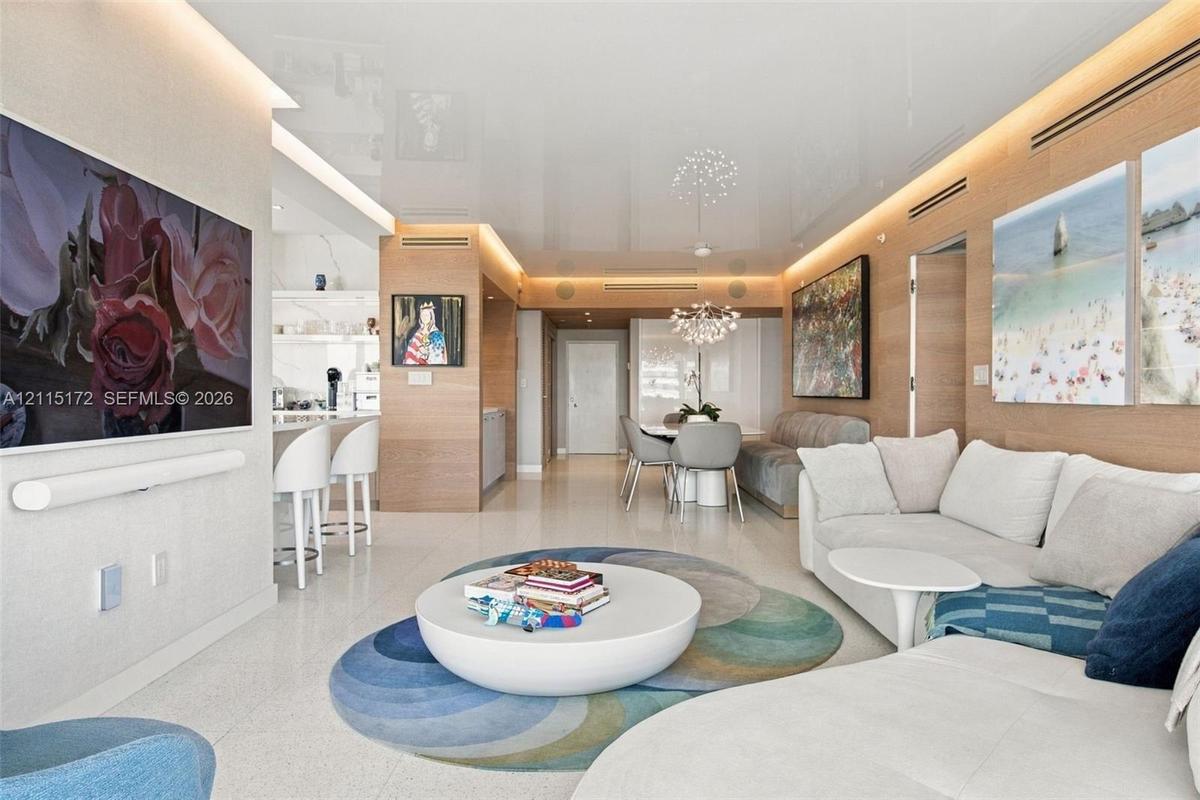 High-gloss ceiling with integrated perimeter recessed lighting, polished stone flooring, and warm wood-panel wall treatments