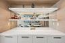 Custom built-in bar featuring white cabinetry, polished solid-surface countertop, mirrored backsplash, and tiered floating shelving with integrated LE