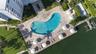 Waterfront grounds featuring a kidney-shaped swimming pool, paved stone decking, landscaped lawn areas, and a dedicated boat dock