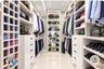 Custom dressing area featuring extensive white built-in cabinetry, floor-to-ceiling storage cubbies, integrated accent lighting, and polished stone fl