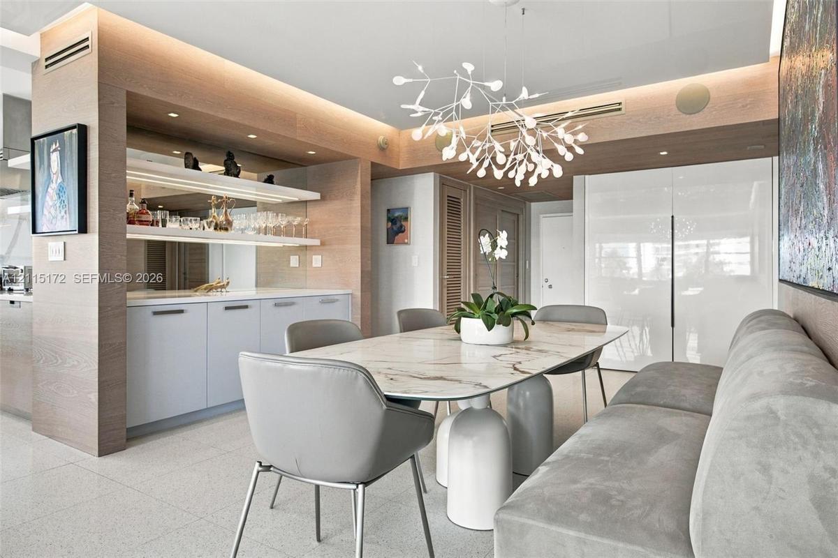 Custom built-in cabinetry with integrated lighting and stone surfacing, complemented by light-toned wood-finish wall paneling, high-gloss cabinetry, a