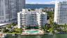 Multi-story residential building featuring private waterfront access, an outdoor swimming pool, a concrete pool deck, and manicured landscaping