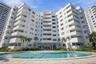 Mid-rise residential building featuring stacked private balconies, a ground-level swimming pool, and stone-paved pool deck