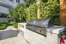 Outdoor kitchen featuring a built-in stainless steel grill, natural stone block counter, and paver hardscaping