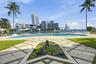 Outdoor space featuring a swimming pool, decorative pond with stone border, paved patio, manicured lawn, and perimeter fencing