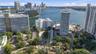 Aerial perspective of high-rise structures featuring water frontage, established landscaping, paved parking areas, and proximity to a coastal waterway