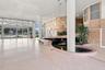 Spacious interior featuring terrazzo flooring, a central decorative pond, full-height glass folding doors, structural cylindrical columns, and pendant