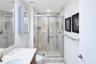 Bathroom featuring a walk-in shower with stone tile surround, chrome sliding glass enclosure, stone countertop vanity, recessed lighting, and a mirror