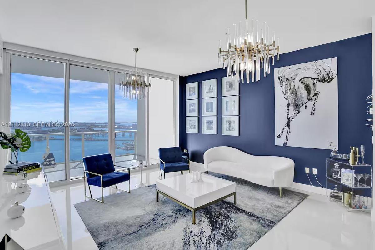 Floor-to-ceiling glass windows, high-gloss tile flooring, dual multi-tiered crystal chandeliers, and an accent wall