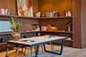 Floor-to-ceiling wood paneling with integrated multi-level shelving, wood-finish flooring, and a stone-topped table with a matte black metal frame