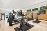 Fitness area featuring full-wall mirrors, recessed lighting, wood-slat accent wall cladding, and floor-to-ceiling glass doors providing natural light