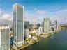 High-rise residential tower featuring a glass-curtain wall exterior, tiered architectural design, multiple private balconies, and a prominent waterfro