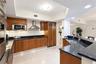 Kitchen featuring wood cabinetry, dark stone countertops, stainless steel appliances including a built-in refrigerator and wall oven, recessed lightin