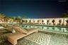 In-ground swimming pool featuring a decorative stone paver deck and a covered patio structure with built-in columns