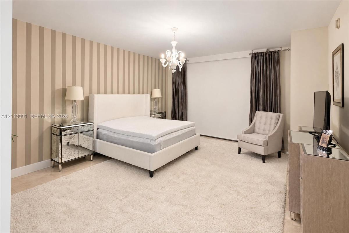 Room featuring vertical-striped accent wall treatment and a decorative multi-arm chandelier