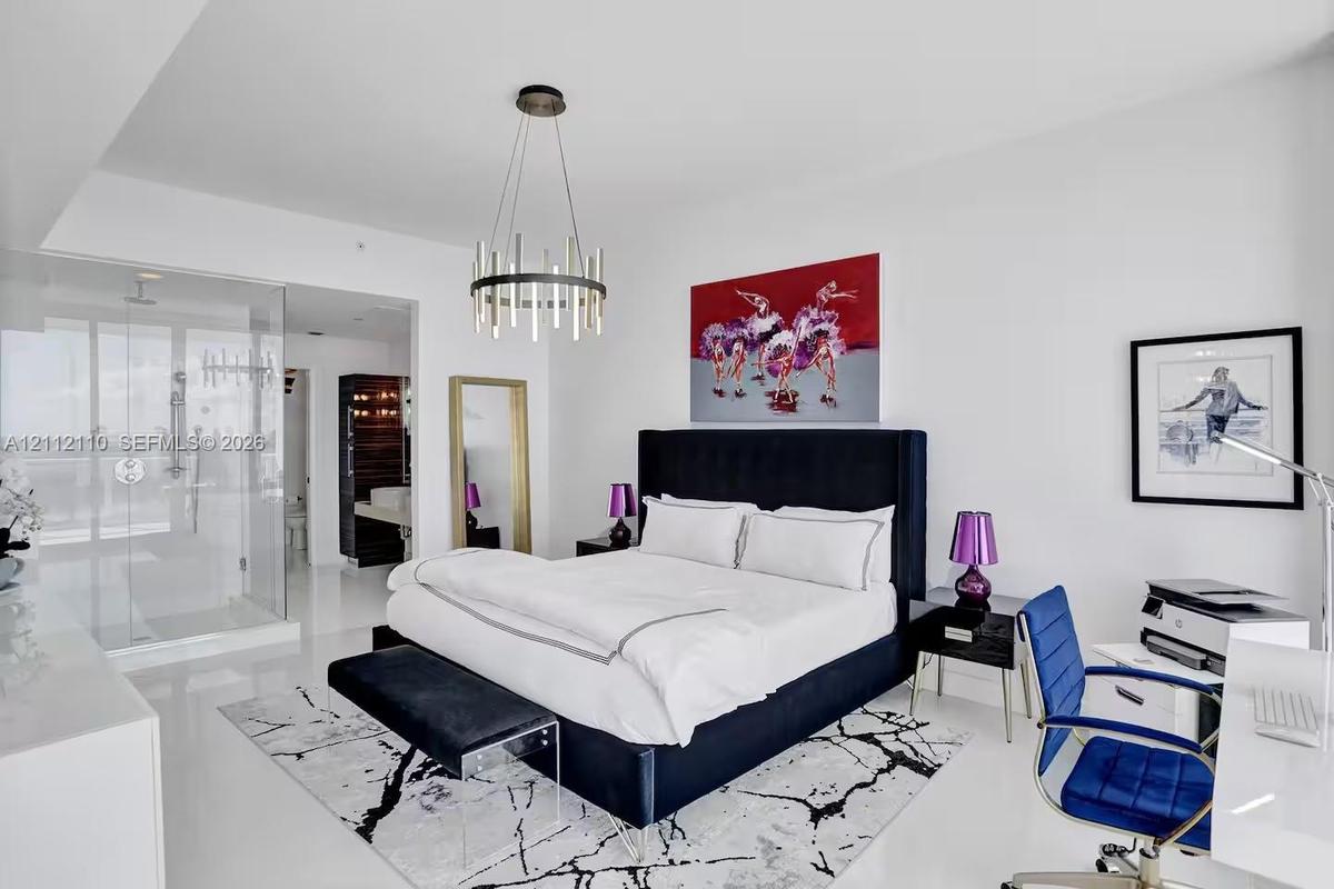 Spacious room featuring high ceilings, polished tile flooring, a contemporary cylindrical chandelier, and an open-concept glass-enclosed shower