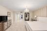 Spacious interior featuring a multi-arm crystal chandelier, wall-to-wall carpeting, and an accent wall with vertical striped wallcovering