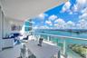 Covered balcony featuring expansive porcelain tile flooring, a glass-panel railing, and panoramic water scenery