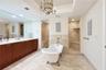 Freestanding soaking tub with claw feet, tile-surround walk-in shower with built-in bench, dual-sink vanity with light-toned countertop, and iron chan