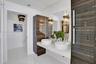 Floating vanity with dual vessel sinks, high-gloss horizontal wood-grain cabinetry, polished white surfaces, and contemporary multi-pendant lighting