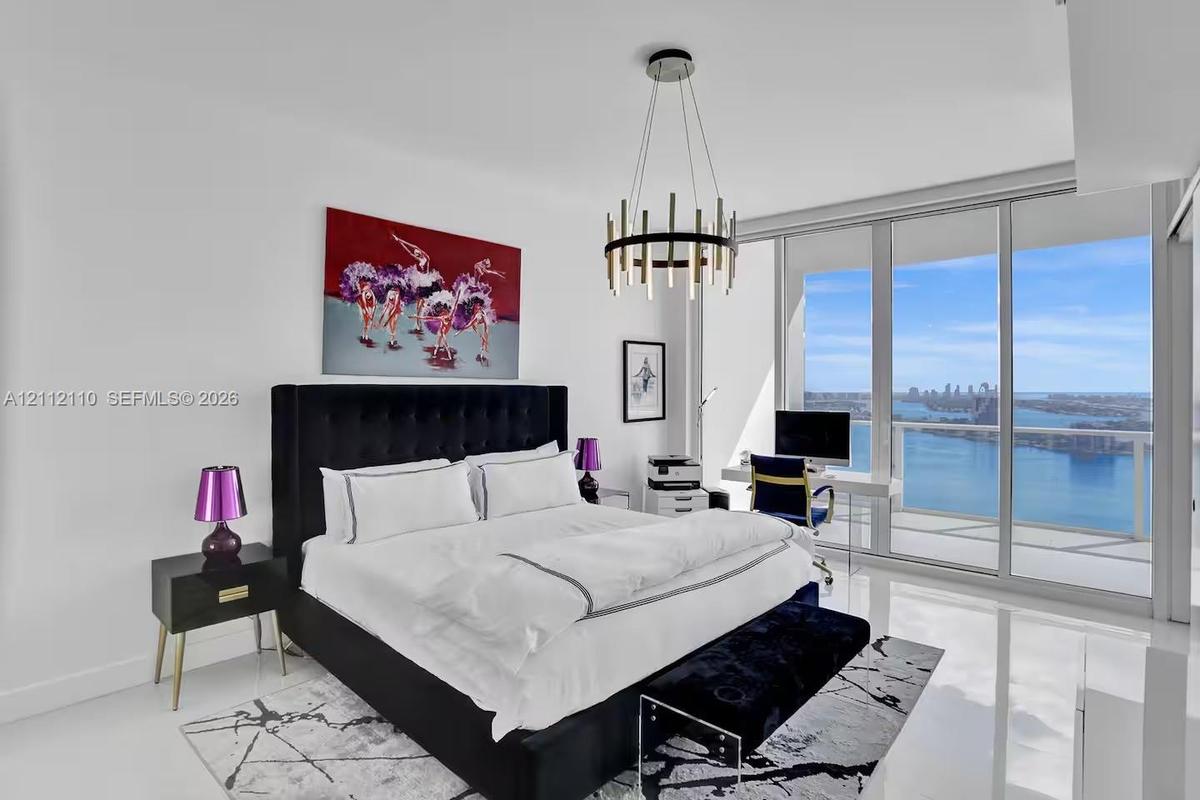 Floor-to-ceiling windows, polished stone flooring, and contemporary metal chandelier