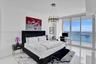 Floor-to-ceiling windows, polished stone flooring, and contemporary metal chandelier