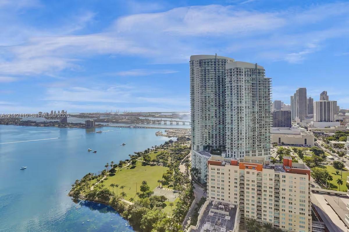 Aerial perspective featuring a high-rise residential tower, waterfront location, and expansive coastal expanse