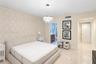 Bedroom featuring patterned accent wallpaper, polished stone flooring, and a tiered crystal chandelier