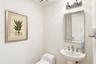 Powder room featuring a wall-mounted pedestal sink with a metallic widespread faucet, a rectangular beveled-edge wall mirror, and overhead decorative 