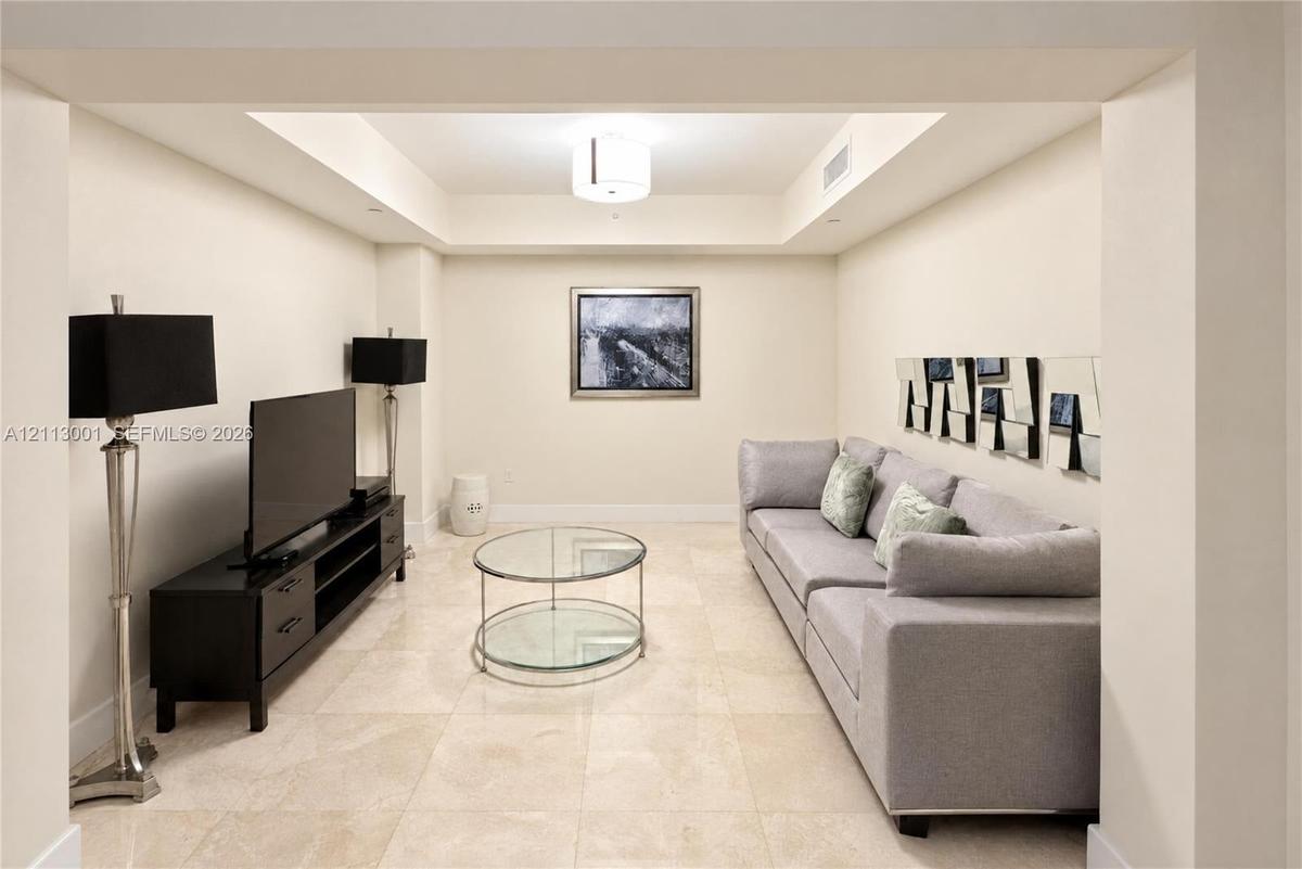 Neutral-toned room featuring a coffered ceiling, recessed lighting, and large-format tile flooring