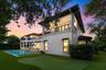 Two-story stucco exterior featuring a tiered roofline, expansive covered balconies with patterned railings, an integrated putting green, and a rectang