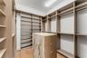Custom walk-in closet featuring extensive built-in shelving, integrated hanging rods, a central island with a stone-finish countertop, and three built