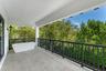 Covered terrace featuring stone-finish flooring, a freestanding soaking tub, custom geometric metal railing, and wall-mounted exterior lighting