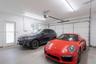 Attached two-car garage featuring white walls, concrete flooring, overhead LED lighting, and a private pedestrian access door