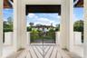 Covered terrace featuring stone flooring, substantial square pillars, and decorative geometric metal railing
