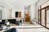 High-ceiling living area featuring large-format tile flooring, double glass doors with wood-finish frames, a recessed tray ceiling, and a staircase wi