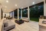 Covered outdoor living area featuring light-toned stone flooring, recessed ceiling lighting, structural support columns, an integrated outdoor kitchen